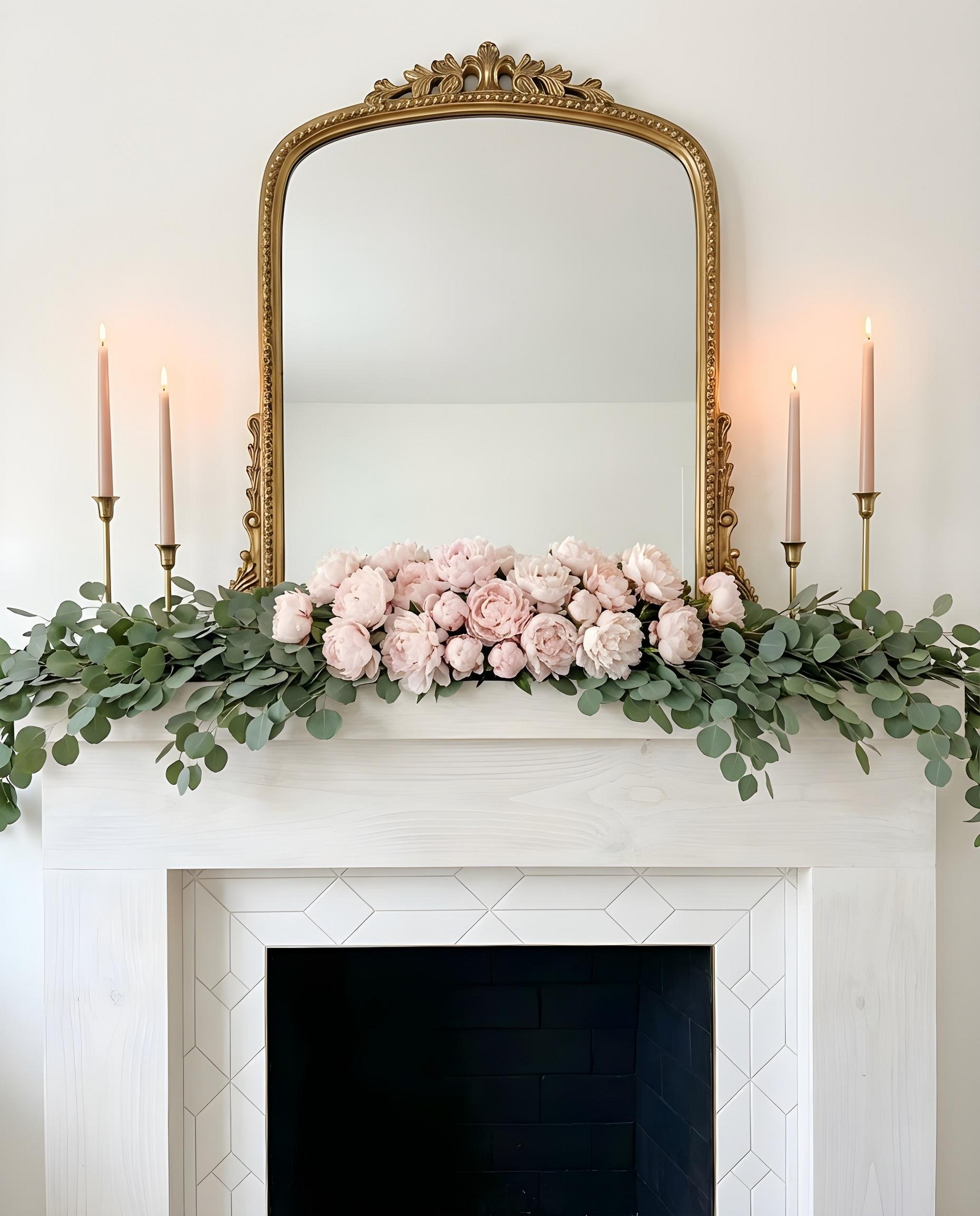 Decorative floral arrangement on a fireplace mantel with a gold mirror above.