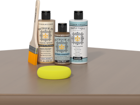 Retique It® Barn Wood kit with brush, Wood’n Primer, Barn Wood stain alternative, satin top coat, and yellow sponge on a wood surface.