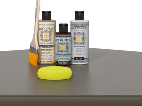 Retique It Black Walnut Kit with Satin Polytique It, Light Wood Wood'n Primer, Black Walnut Gel Stain Alternative, paintbrush, and yellow sponge on a tabletop.