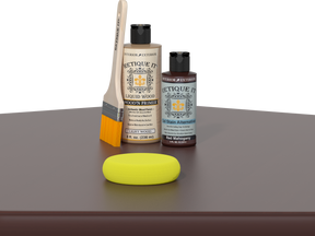 Retique It® Red Mahogany Kit with Light Wood’n Primer, Red Mahogany Gel Stain Alternative, paintbrush, and yellow sponge on a red mahogany tabletop.