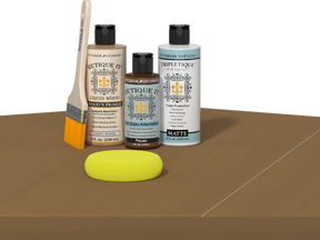 Retique It® Light Wood kit with brush, Wood’n Primer, Pecan stain alternative, and yellow sponge on a wood surface.