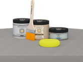 Retique It® Weathered Wood Multipurpose Kit contents with Light Wood Liquid Wood primer, Weathered Wood gel stain alternative, PolyTique It® matte exterior top coat, paintbrush, and yellow sponge displayed on a gray wood surface.