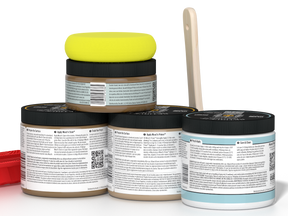 Five paint cans with lids stacked on a white background