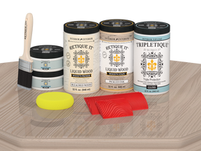 Sun-bleached Wood'n Finish Kit by Retique It® with four large wood finishing products on a table, glossy wood surface.
