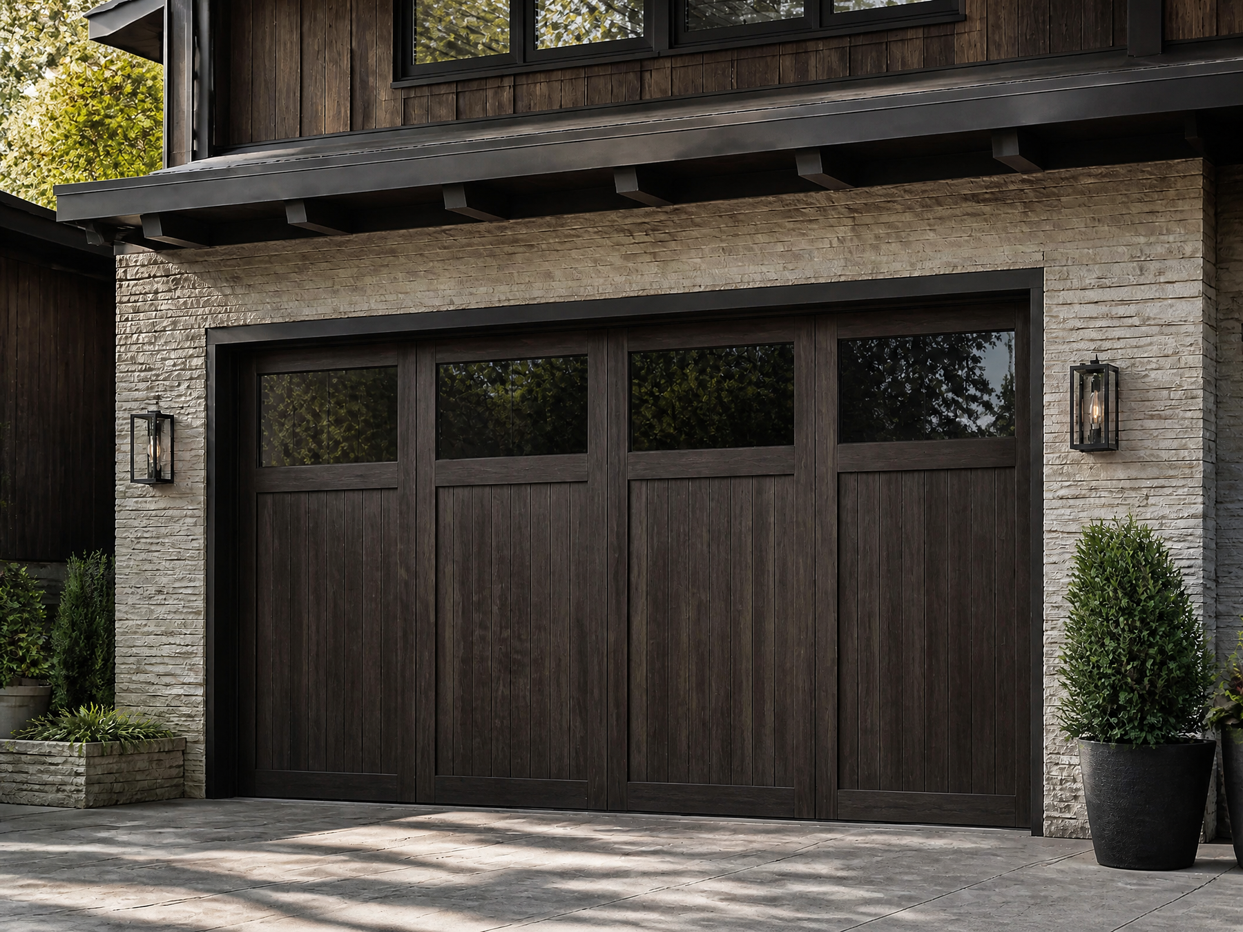 Dark brown wooden garage doors with small rectangular windows, installed on a stone and wood exterior of a house.